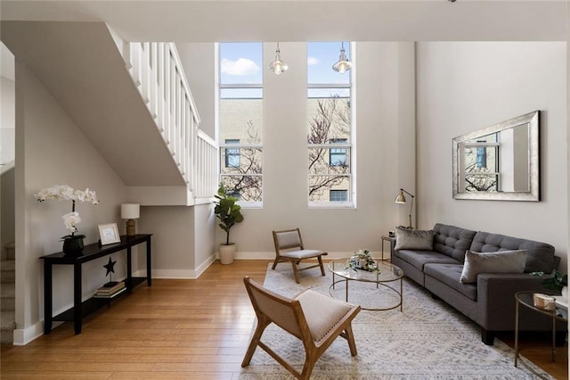 living room featuring baseboards, stairs, and light wood finished floors