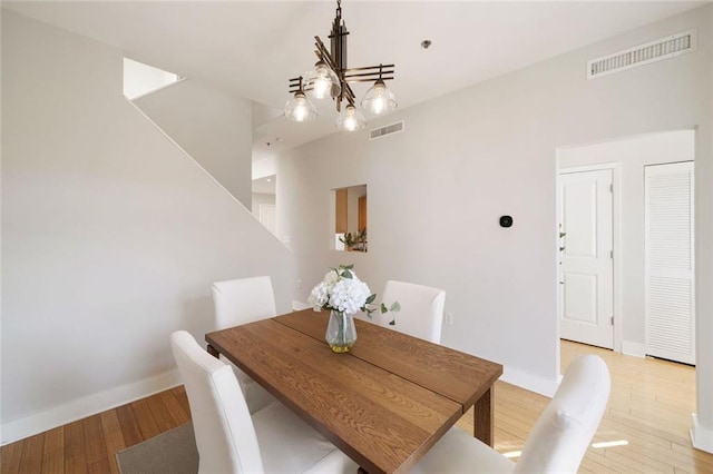 dining space with visible vents, baseboards, light wood-type flooring, and an inviting chandelier