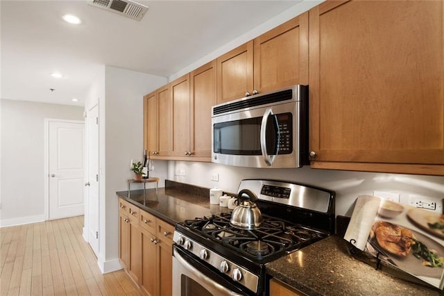 kitchen with dark stone countertops, visible vents, light wood finished floors, recessed lighting, and appliances with stainless steel finishes