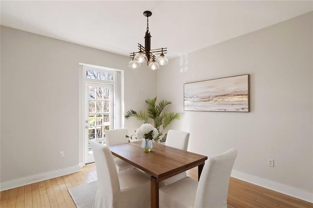 dining area with baseboards, a notable chandelier, and light wood-style flooring