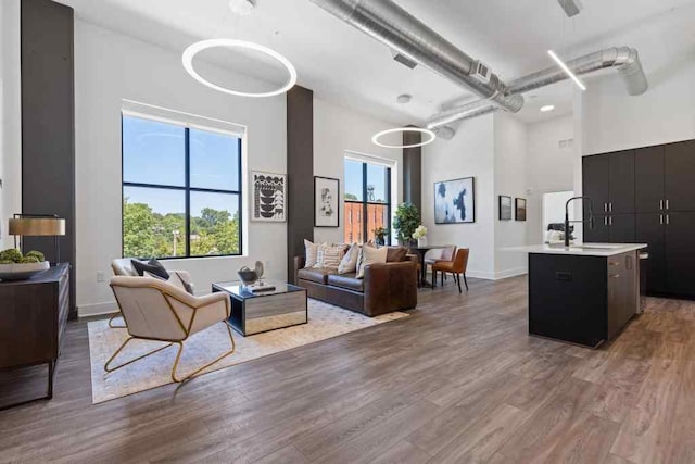 living room with a towering ceiling, wood-type flooring, and a healthy amount of sunlight