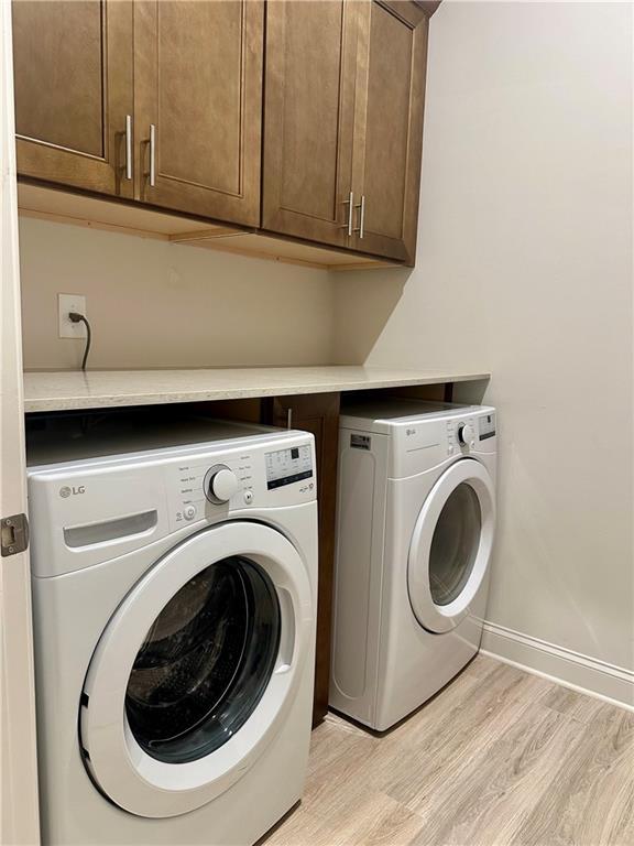 619 Linger Longer Dr, Ellijay, GA 30540 - laundry area with washing machine and clothes dryer, cabinet space, and light wood-style flooring