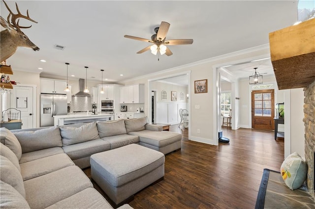 living area featuring dark wood finished floors, visible vents, ornamental molding, a ceiling fan, and baseboards