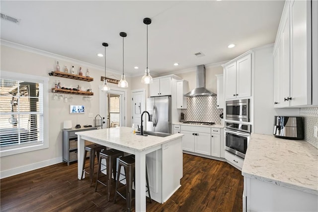 kitchen featuring wall chimney exhaust hood, white cabinetry, visible vents, and stainless steel appliances