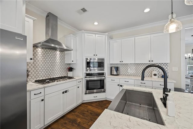 kitchen featuring visible vents, wall chimney exhaust hood, white cabinets, and stainless steel appliances