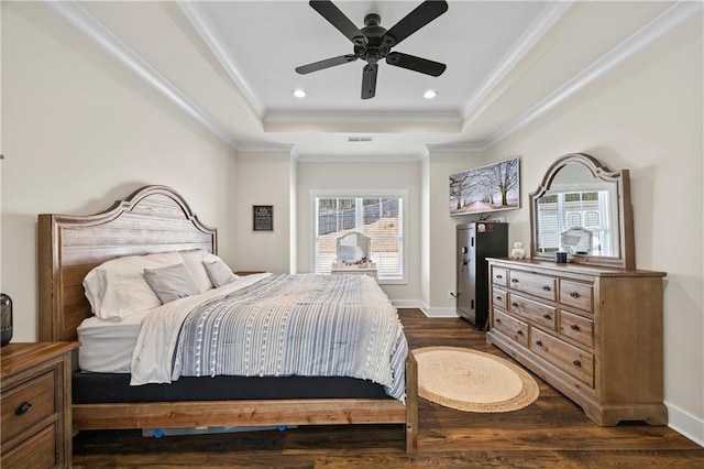 bedroom with dark wood-style floors, a tray ceiling, ornamental molding, and baseboards