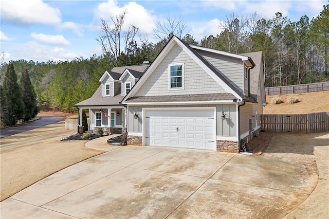 view of front of home with driveway, stone siding, fence, and board and batten siding