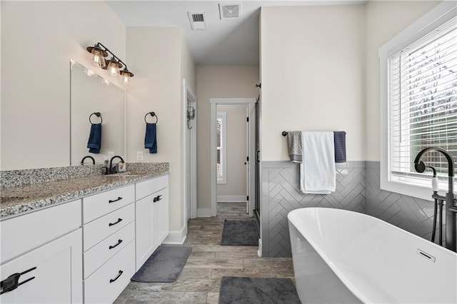 bathroom with visible vents, plenty of natural light, and a freestanding bath