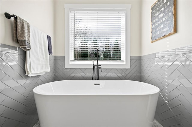 full bath with a freestanding bath and a wainscoted wall