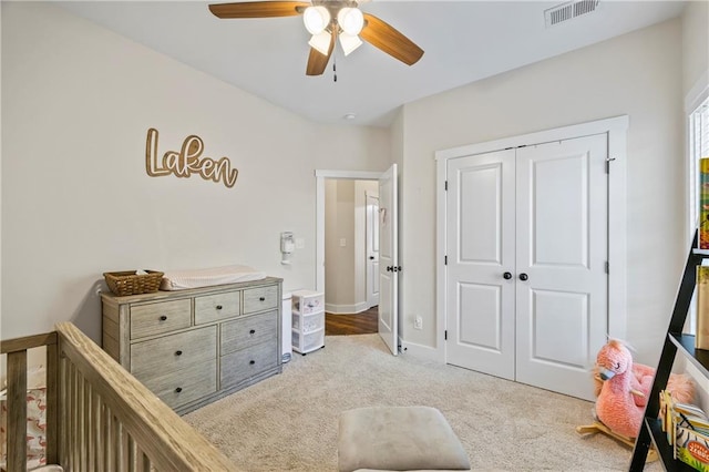 bedroom with a crib, baseboards, visible vents, carpet, and a closet