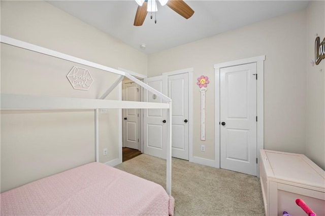 bedroom with light carpet, ceiling fan, and multiple closets