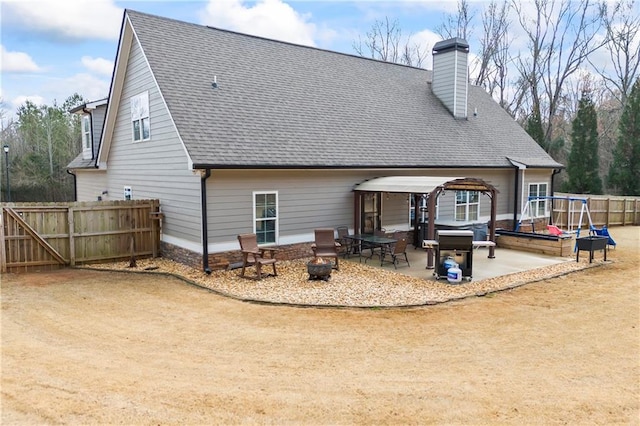 rear view of property featuring a shingled roof, a chimney, a patio area, and fence