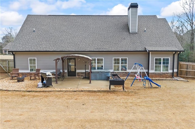 back of house featuring a fire pit, a patio, fence, and a hot tub