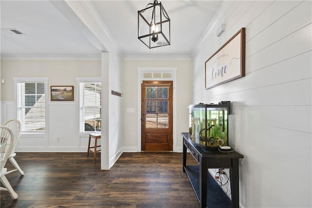 foyer entrance featuring a wealth of natural light, ornamental molding, dark wood-type flooring, and an inviting chandelier