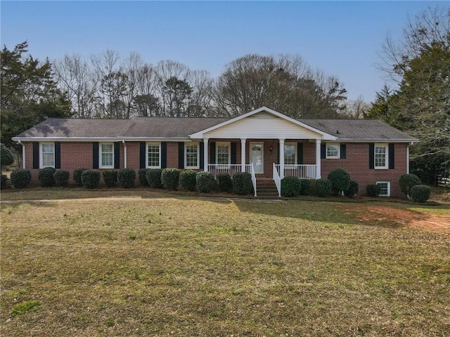 single story home featuring a porch, a front yard, and brick siding