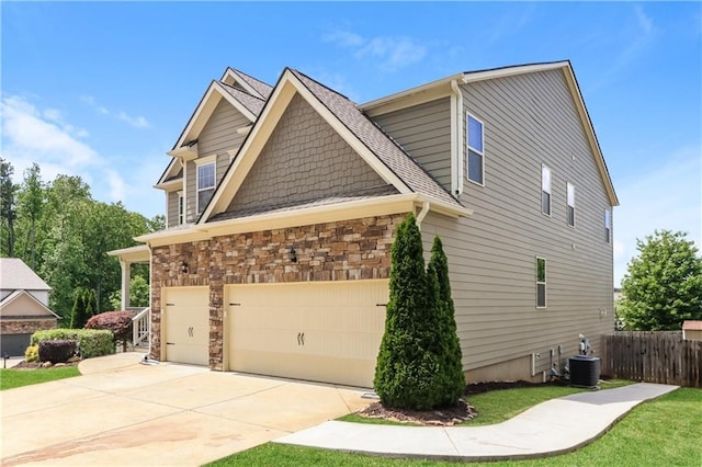 626 Discovery Ct, Acworth, GA 30102 - view of home's exterior featuring fence, stone siding, central AC unit, concrete driveway, and a lawn