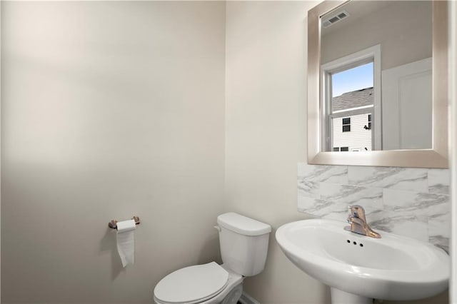 bathroom with sink, decorative backsplash, and toilet