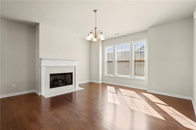 unfurnished living room featuring dark wood-type flooring and an inviting chandelier