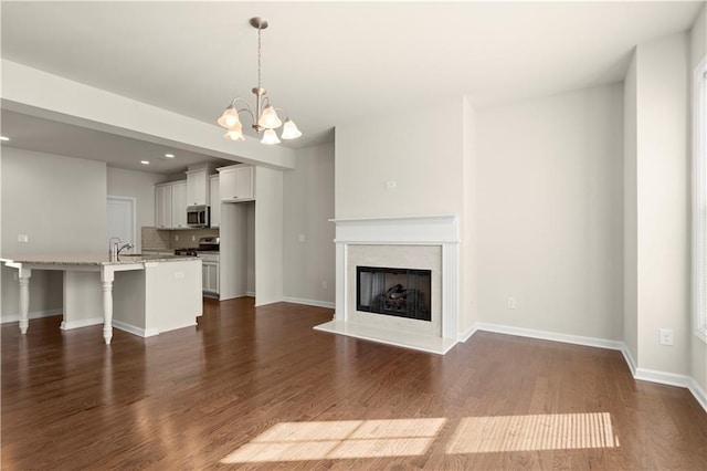 unfurnished living room featuring dark wood-type flooring and a notable chandelier