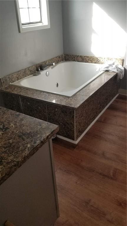 bathroom with wood-type flooring and tiled tub