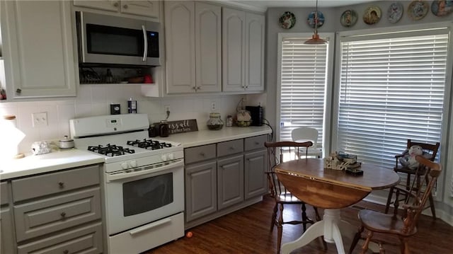 kitchen with hanging light fixtures, dark hardwood / wood-style floors, gray cabinets, white range with gas cooktop, and decorative backsplash