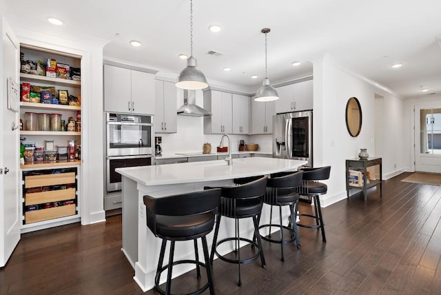 209 Floral Valley Dr, Woodstock, GA 30188 - kitchen with appliances with stainless steel finishes, wall chimney range hood, a sink, light countertops, and dark wood-type flooring
