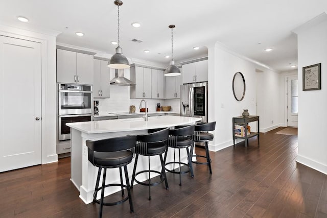 209 Floral Valley Dr, Woodstock, GA 30188 - kitchen featuring appliances with stainless steel finishes, wall chimney range hood, light countertops, a kitchen breakfast bar, and baseboards