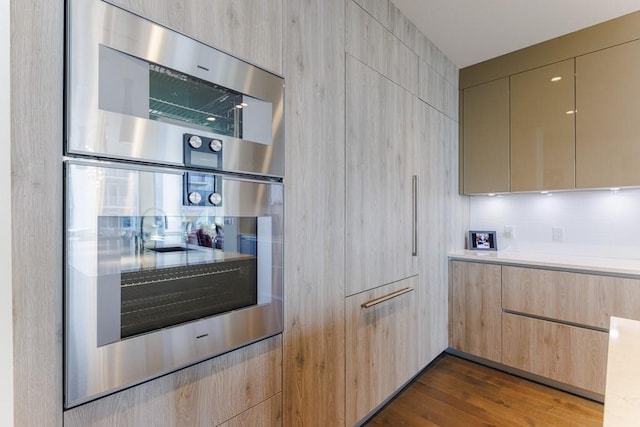 kitchen featuring light brown cabinetry, dark hardwood / wood-style floors, and double oven