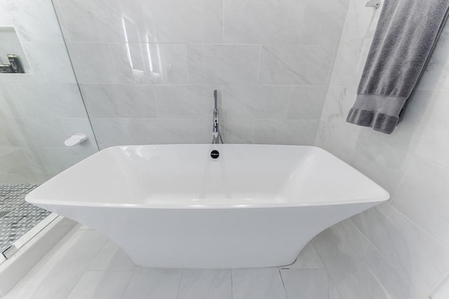 bathroom with a washtub and tile walls