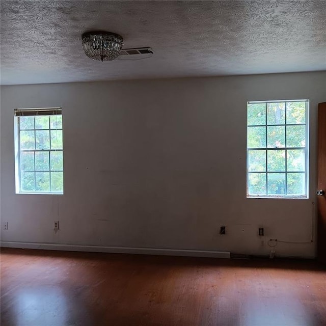 spare room featuring wood-type flooring and a textured ceiling