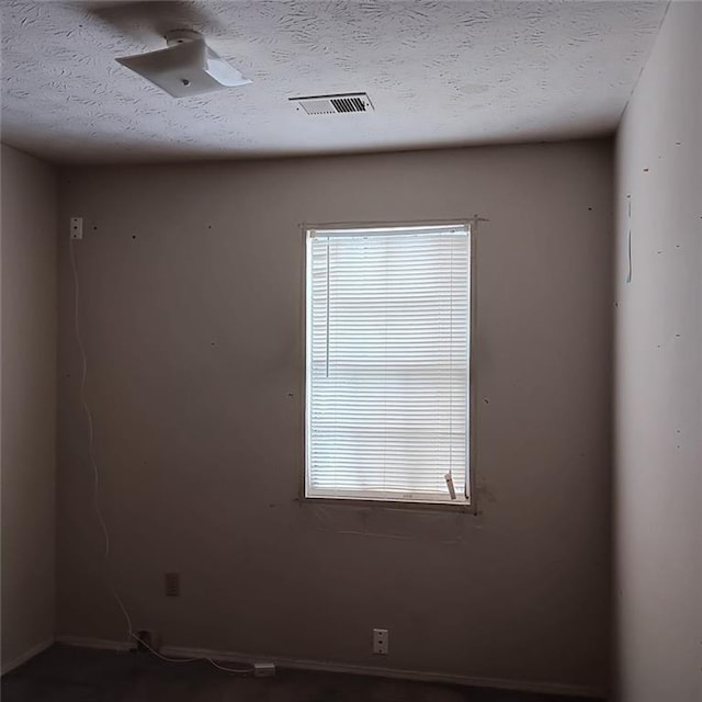 unfurnished room with a textured ceiling