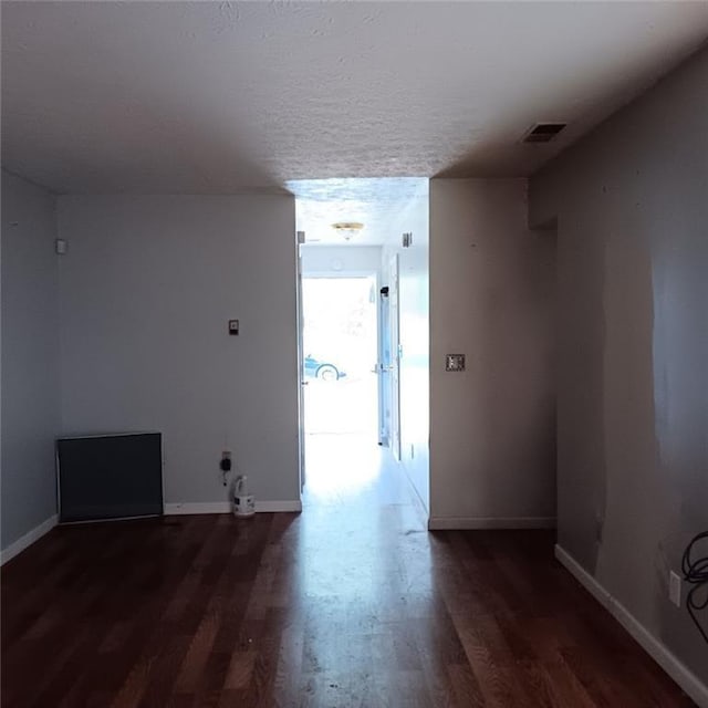 unfurnished room featuring dark hardwood / wood-style flooring and a textured ceiling