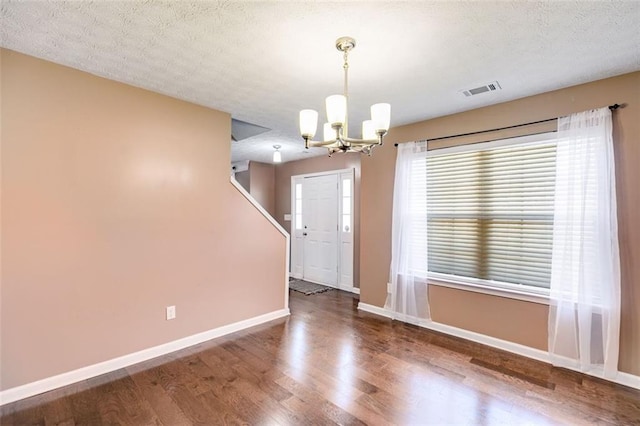 empty room with hardwood / wood-style floors, a textured ceiling, and a chandelier