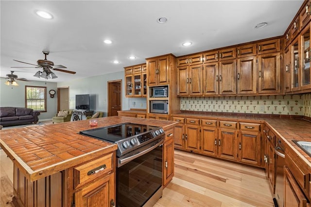 294 Hillcrest Hts, Cornelia, GA 30531 - kitchen with appliances with stainless steel finishes, tile countertops, brown cabinets, light wood-style flooring, and a kitchen island