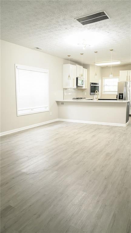 623 Shadowmoore Dr, Riverdale, GA 30274 - unfurnished living room featuring a textured ceiling and light wood-style floors