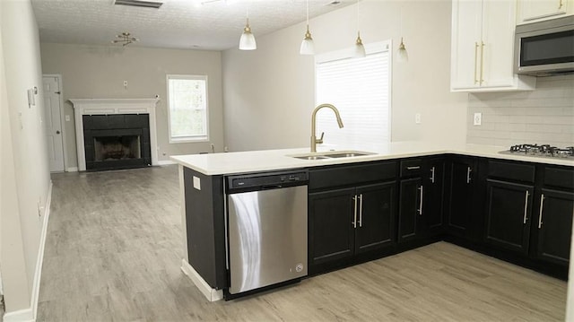 623 Shadowmoore Dr, Riverdale, GA 30274 - kitchen featuring appliances with stainless steel finishes, light wood finished floors, backsplash, a peninsula, and a textured ceiling