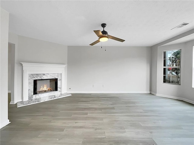 unfurnished living room with ceiling fan, light wood-type flooring, and a fireplace