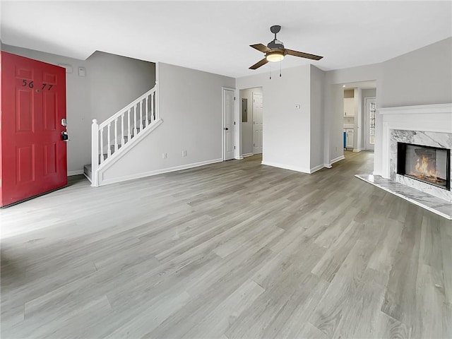 unfurnished living room with ceiling fan, a fireplace, and light hardwood / wood-style floors