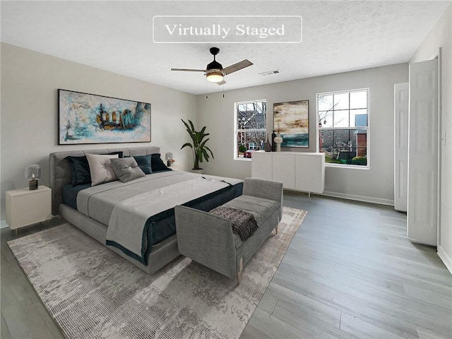 bedroom featuring multiple windows, ceiling fan, a textured ceiling, and light wood-type flooring