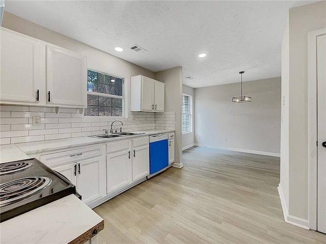 kitchen featuring backsplash, white dishwasher, sink, white cabinets, and hanging light fixtures