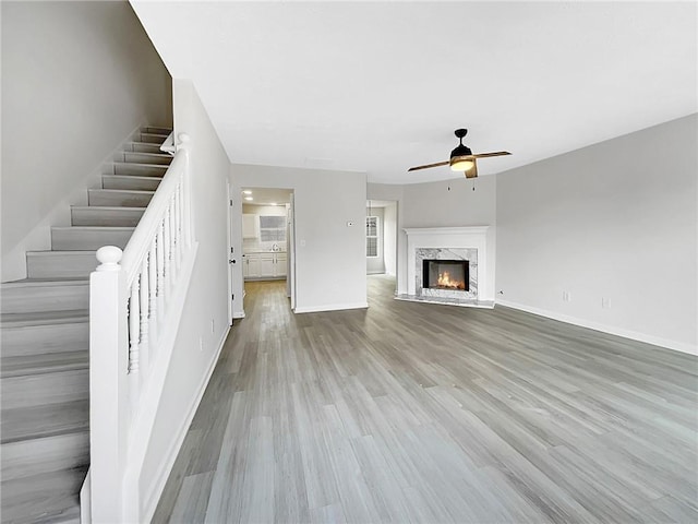 unfurnished living room with ceiling fan, light hardwood / wood-style floors, and a fireplace