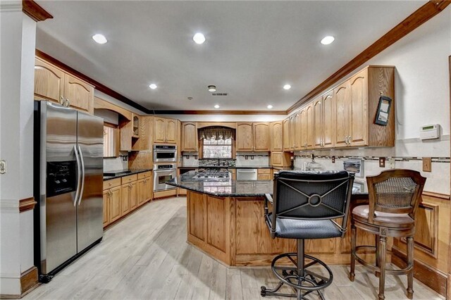 kitchen with a center island, dark stone counters, light hardwood / wood-style floors, a kitchen bar, and appliances with stainless steel finishes