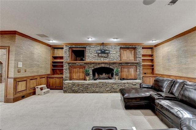 carpeted living room featuring built in shelves, a stone fireplace, and ornamental molding