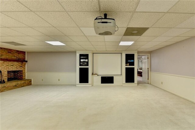 interior space with a paneled ceiling, carpet floors, and a brick fireplace