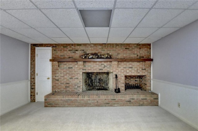 unfurnished living room featuring a fireplace, carpet floors, and a drop ceiling