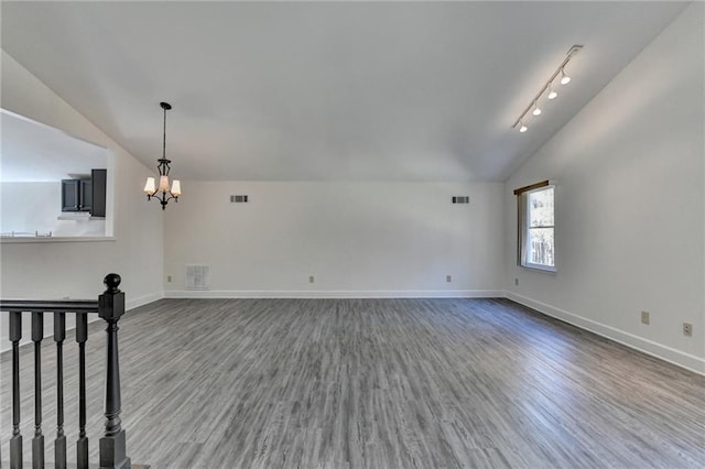 unfurnished living room with a chandelier, hardwood / wood-style floors, rail lighting, and vaulted ceiling