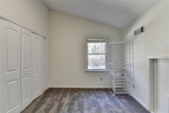 unfurnished bedroom featuring lofted ceiling, a closet, and dark colored carpet