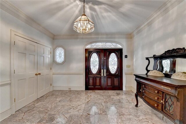 foyer with ornamental molding and an inviting chandelier