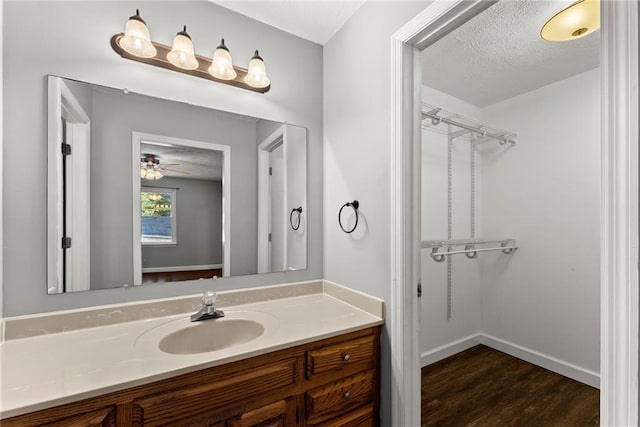 bathroom with ceiling fan, hardwood / wood-style floors, a textured ceiling, and vanity