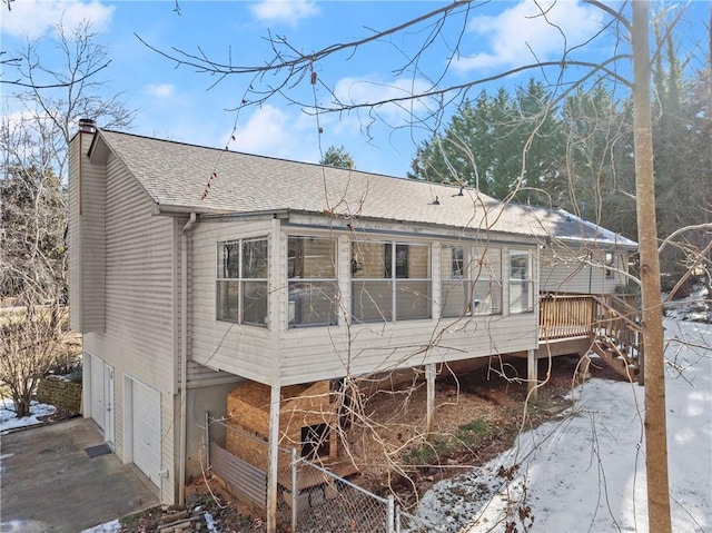 snow covered house featuring a deck and a garage